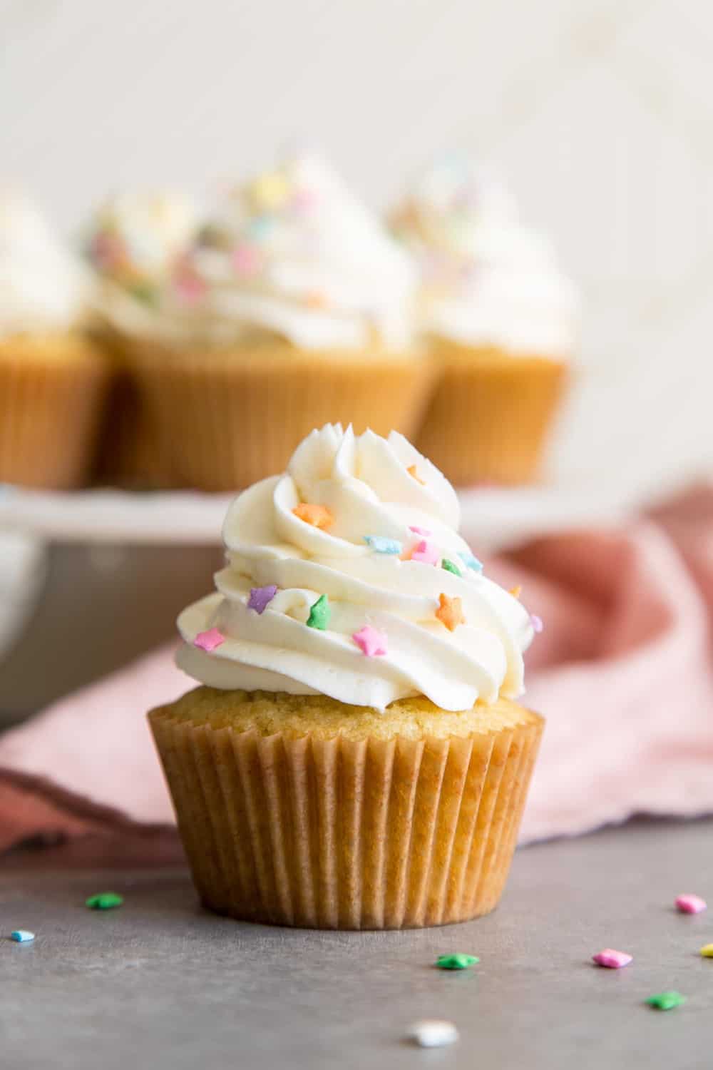 A vanilla cupcake with white frosting and star sprinkles